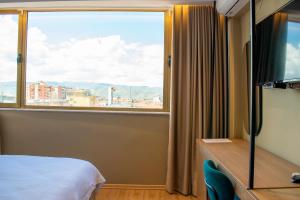 Zimmer mit einem Bett und einem großen Fenster in der Unterkunft Bocca Hotel Korce in Korçë