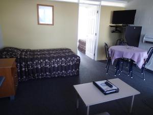 sala de estar con sofá, mesa y TV en Mountain View Motel, en Taupo