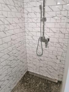 a white tiled shower with a hose in a bathroom at Studio vue mer sur les hauteurs de Lanzarote in Las Breñas