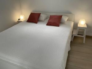 a large white bed with two red pillows on it at Studio vue mer sur les hauteurs de Lanzarote in Las Breñas