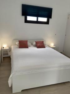 a large white bed with two red pillows on it at Studio vue mer sur les hauteurs de Lanzarote in Las Breñas