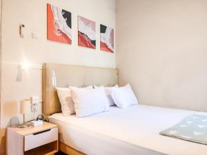 ein Schlafzimmer mit einem weißen Bett und einem Nachttisch in der Unterkunft SleepHouse 2BR Cozy Place for StayCation in Cirebon