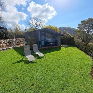 two chairs and a house on a grass field at Sauerland-Tinyworld - Ihr Tiny Ferienhaus im Sauerland am Diemelsee in Diemelsee