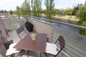 een tafel en stoelen op een balkon met uitzicht op een rivier bij Apartman Via Casa in Vinkovci