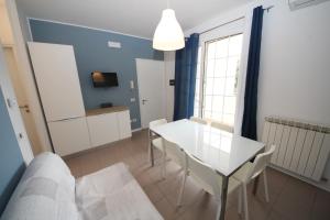 sala de estar con mesa blanca y sillas en Residence Verdena appartamento 02 en Rosolina Mare