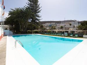 uma grande piscina azul com uma cidade ao fundo em Bungalows Caribe em Puerto Rico de Gran Canaria