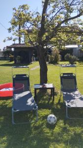 three chairs and a table and a tree with a soccer ball at Mansarda al mare in Pertegada