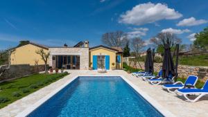 una piscina con sillas y una casa en Villa Iria Bella, en Marčana