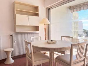 d'une salle à manger avec une table, des chaises et une fenêtre. dans l'établissement Appartement Le Lavandou, 1 pièce, 2 personnes - FR-1-251-224, au Lavandou