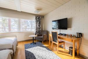 um quarto com uma cama, uma secretária e uma televisão em Hotel Rantapuisto em Helsinque