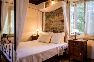 1 dormitorio con cama y pared de piedra en Perleas, en Kambos