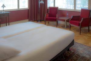 a bedroom with a large bed and two chairs at Hotel Konbanwa in Heilig Landstichting