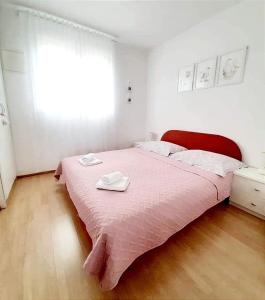 a bedroom with a pink bed with two towels on it at Apartment Anita in Trogir