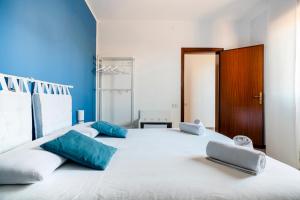 Una gran cama blanca con almohadas azules. en IL MONTE - Suite Con Terrazza Panoramica, en Erice