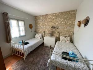 1 dormitorio con 2 camas y pared de piedra en La Petite Auberge - Gîtes, en Razac-dʼEymet