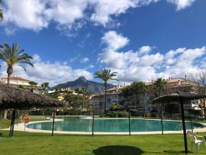 een zwembad in een resort met palmbomen en gebouwen bij La Dama de Noche - Marbella Puerto Banus in Marbella