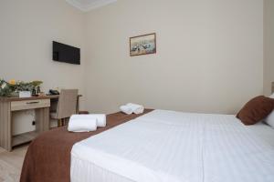 a bedroom with a large white bed and a desk at Daisi Sunset Hotel in Batumi