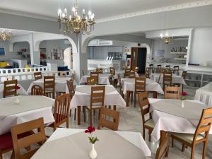 a restaurant with white tables and chairs and a chandelier at Albatros Hotel in Karterados