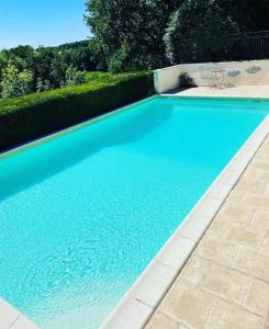 a swimming pool with blue water in a yard at La Petite Auberge - Gîtes in Razac-dʼEymet