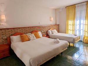 een slaapkamer met 2 bedden en een bakstenen muur bij Hotel Moregón in Cuacos de Yuste