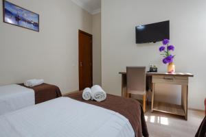 a hotel room with two beds and a desk and a television at Daisi Sunset Hotel in Batumi