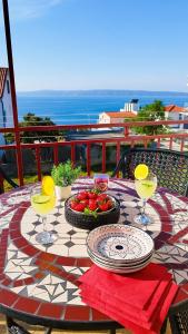 a table with a bowl of fruit and wine glasses at Apartment Anita in Trogir