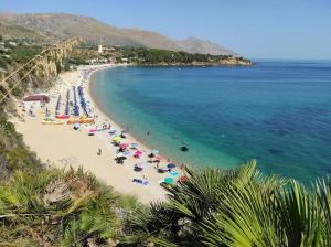 ein Strand mit Sonnenschirmen und Menschen im Wasser in der Unterkunft Villa Corallo - Scopello Guidaloca Bay in Scopello