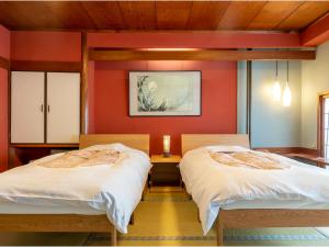 two beds in a room with red walls at Yanagiso in Toyooka