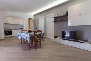eine Küche und ein Esszimmer mit einem Tisch und einem TV in der Unterkunft Villa Corallo - Scopello Guidaloca Bay in Scopello