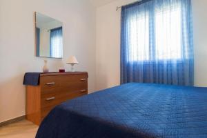 ein Schlafzimmer mit einem blauen Bett, einer Kommode und einem Spiegel in der Unterkunft Villa Corallo - Scopello Guidaloca Bay in Scopello