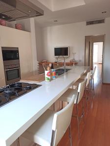 una cucina con un grande piano di lavoro bianco e sedie di Attico San Domenico a Trapani