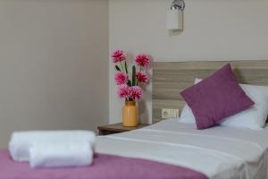 a bed with a vase with pink flowers in it at Daisi Sunset Hotel in Batumi