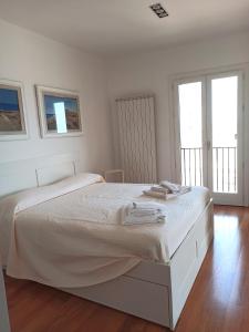 una camera bianca con un grande letto con due finestre di Attico San Domenico a Trapani