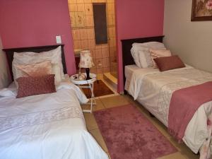 two beds in a room with pink walls at Victorian Villa Westdene Benoni in Benoni