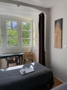 a bedroom with a bed and a table and windows at Hôtel Patricia - Strasbourg Hyper Centre in Strasbourg