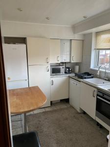 eine Küche mit weißen Geräten und einem Holztisch in der Unterkunft Lux Homes in Sunbury Common