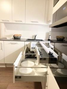 una cocina con armarios blancos y platos blancos en un horno en Scandinavian Apartment Hotel - Lunden 1 - Central 3 bedroom apartment on two floors, en Horsens