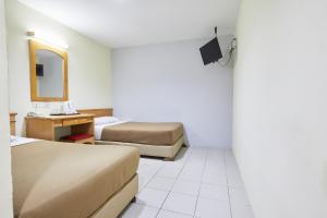 ein Hotelzimmer mit 2 Betten, einem Schreibtisch und einem Spiegel in der Unterkunft Tang City Hotel at Petaling Street in Kuala Lumpur