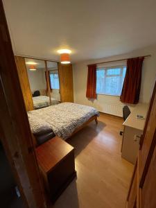 Schlafzimmer mit einem Bett, einem Schreibtisch und Fenstern in der Unterkunft Lux Homes in Sunbury Common