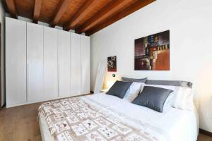 Centro storico Bilocale Check in 24h Wi-Fi Bus 500m في Borgo di Terzo: غرفة نوم بيضاء بسرير كبير وسقف خشبي