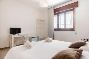 Dos camas en una habitación con escritorio y televisión. en IL MONTE - Suite Con Terrazza Panoramica, en Erice