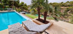 uma piscina com duas espreguiçadeiras ao lado de uma palmeira em * THE CRYSTAL BAY * Luxury bay and see view Villa em Cala Pi