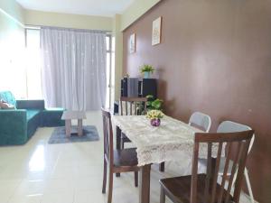 ein Wohnzimmer mit einem Tisch, Stühlen und einem Sofa in der Unterkunft Lagenda Condominium Melaka in Malakka