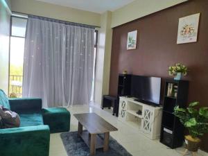 ein Wohnzimmer mit einem Sofa, einem TV und einem Tisch in der Unterkunft Lagenda Condominium Melaka in Malakka