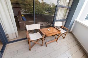 a small balcony with a wooden table and two chairs at Warwick Centre Furnished and Serviced Apartments in Nairobi