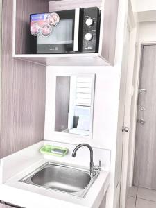 a small kitchen with a sink and a microwave at Arkisha’s Cozy Place in Manila