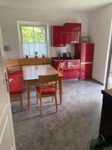 a kitchen with red cabinets and a wooden table and chairs at Casa Andrea Apartment mit Balkon in Wallersdorf
