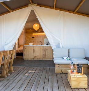 a living room with a tent with a couch and a table at Camping Village Il Gineprino in Marina di Bibbona