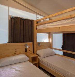 una camera con 2 letti a castello e una finestra di Camping Village Il Gineprino a Marina di Bibbona