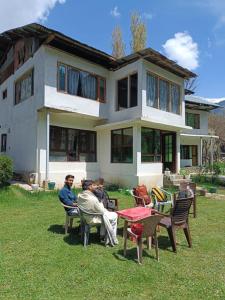 un grupo de personas sentadas frente a una casa en Al-Ayaan Guest House en Pahalgām